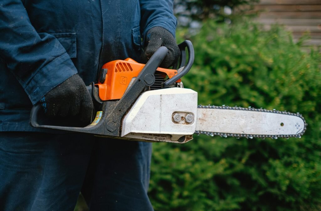 Close-up of a worker holding a chainsaw, highlighting carpentry tools and industry equipment.